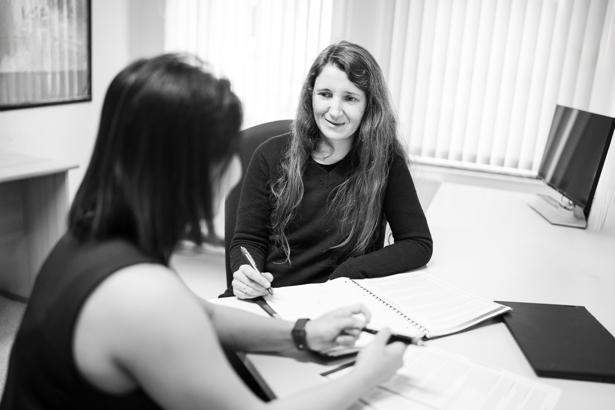 Zwei Frauen im Gespräch an einem Schreibtisch